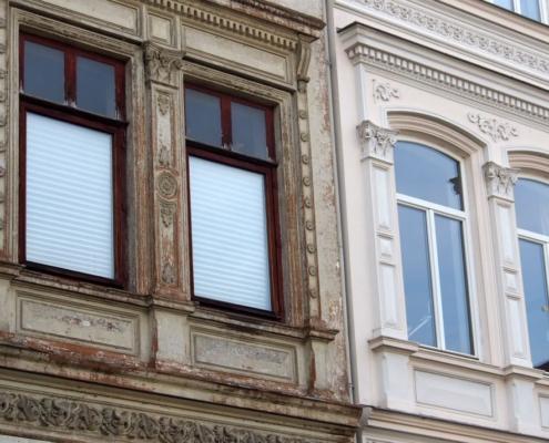 Altbau Sanierung: Vergleich von unsanierter und sanierter Fassade eines Altbaus mit alten und neuen Fenstern