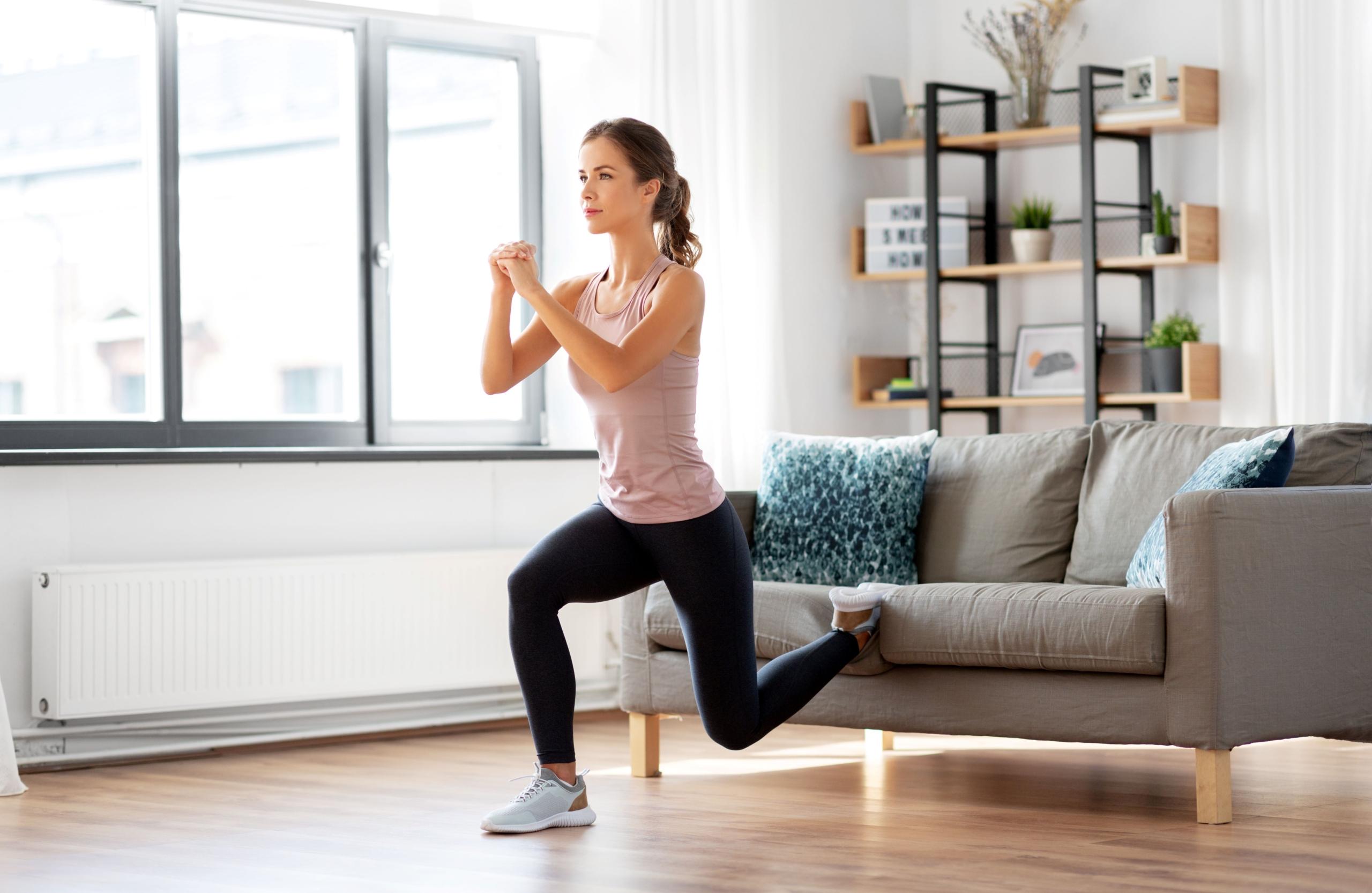 Konzept für Sport, Fitness und gesunden Lebensstil - junge Frau trainiert zu Hause