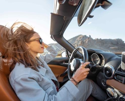 Glückliche Frau fährt Cabrio, während sie auf der Wüstenstraße unterwegs ist. Sorgloses Lifestyle- und Reisekonzept