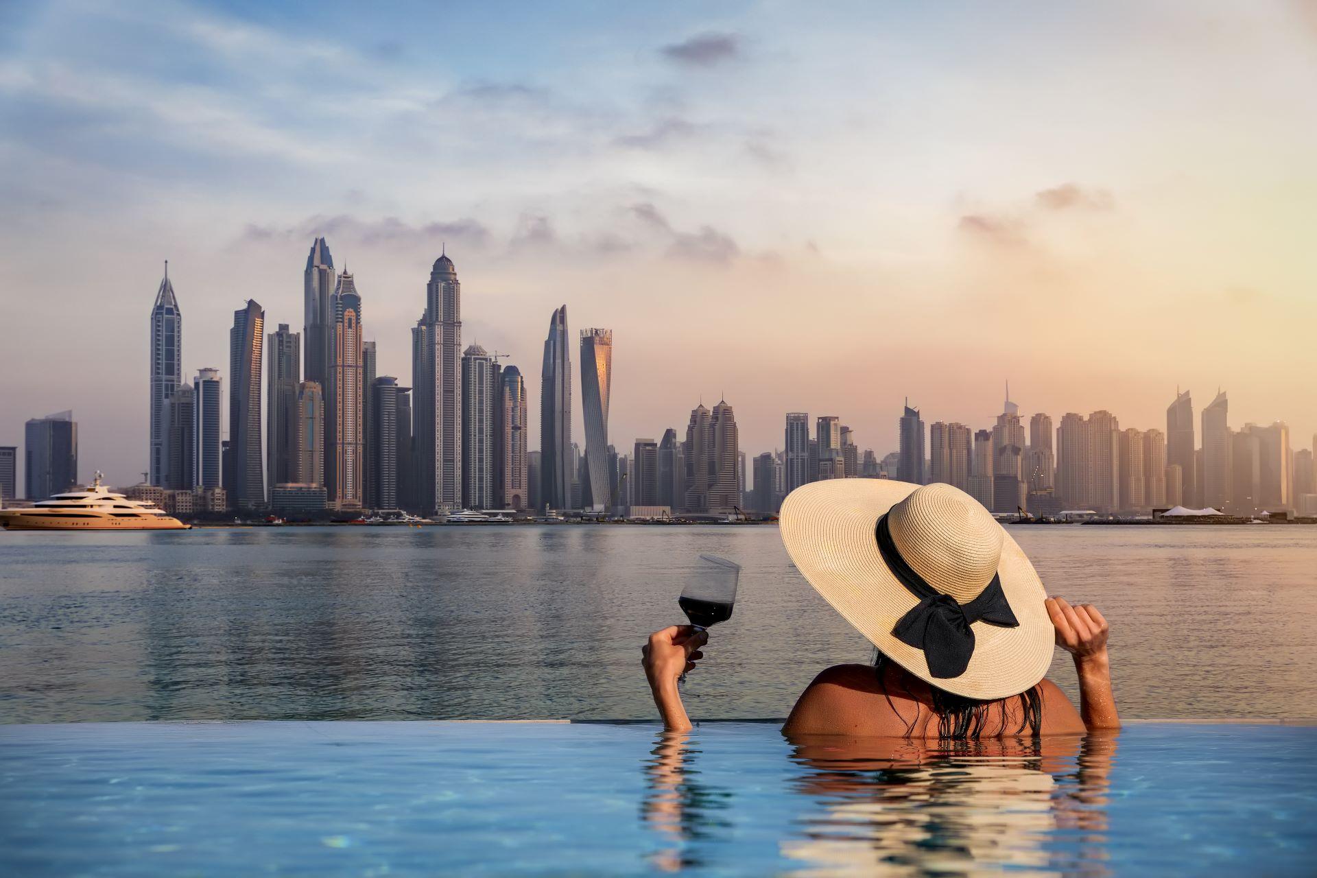 Frau im Infinity-Pool mit Blick auf die Skyline von Dubai.