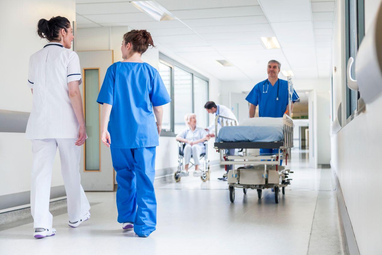 Pflegekräfte im Krankenhausflur, Betreuung von Patienten und interdisziplinäre Teamarbeit während der Ausbildung Pflegehelfer