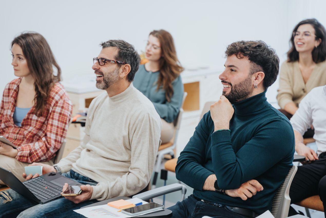 Erwachsene Personen sitzen in einem Schulungsraum und lachen – Symbolbild für Weiterbildung im Rahmen der Betreuungsassistent Ausbildung