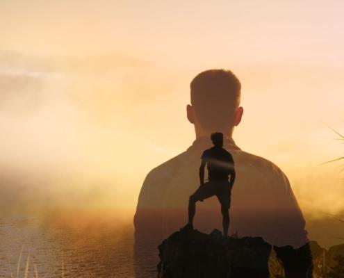 Mann auf Berggipfel bei Sonnenaufgang – Selbstmanagement Coaching