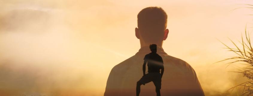 Mann auf Berggipfel bei Sonnenaufgang – Selbstmanagement Coaching