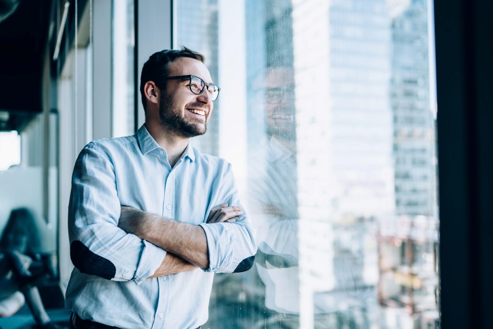 Lächelnder Mann am Fenster – Selbstmanagement Coaching Balance