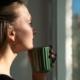 Nachdenkliche Frau mit Tasse am Fenster | Elfliq Liquid