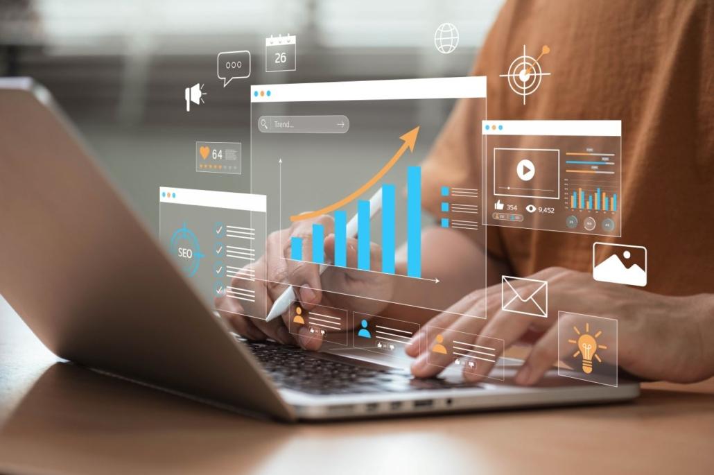 Haende am Laptop mit digitalen Inhalten wie Erklaervideo, SEO-Daten, Icons und Statistiken zur Content-Optimierung