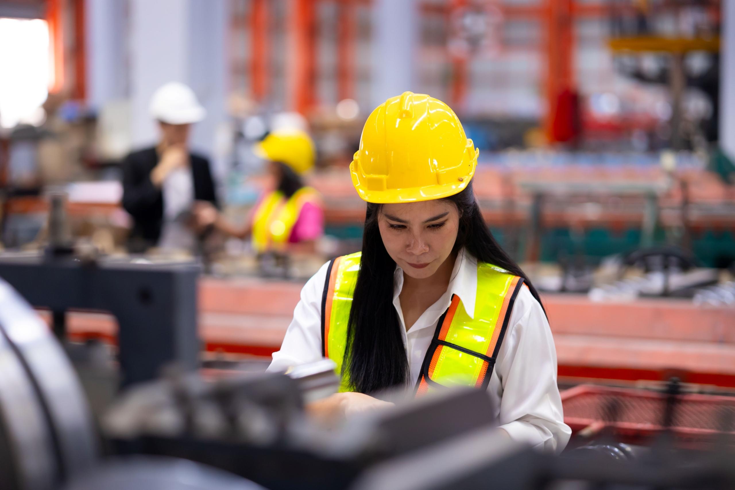 Fachkraft mit Schutzhelm arbeitet effizient dank Produktionsplanung Software im industriellen Umfeld
