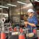 Mitarbeiter mit Helm nutzt Produktionsplanung Software auf Tablet in moderner Fertigungshalle