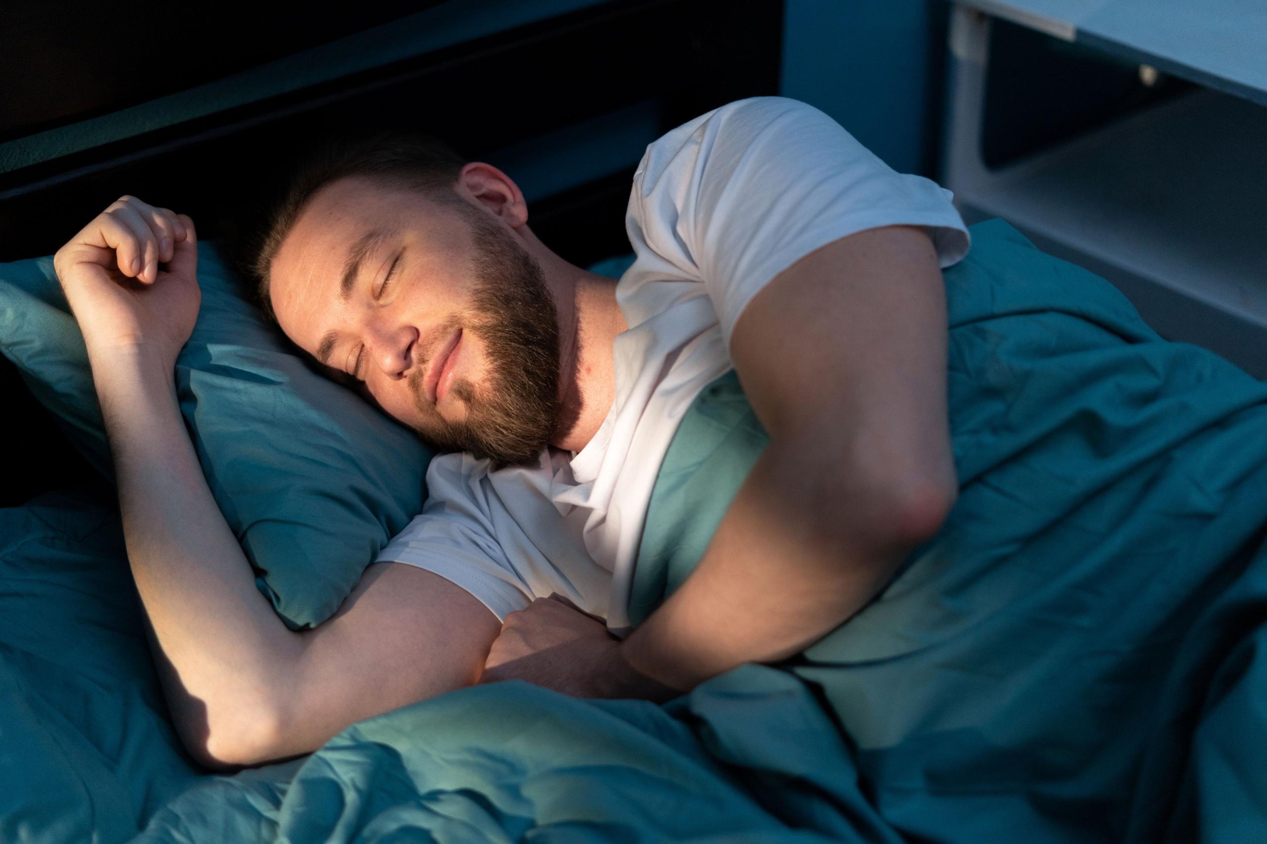 Mann schläft entspannt in seinem Bett