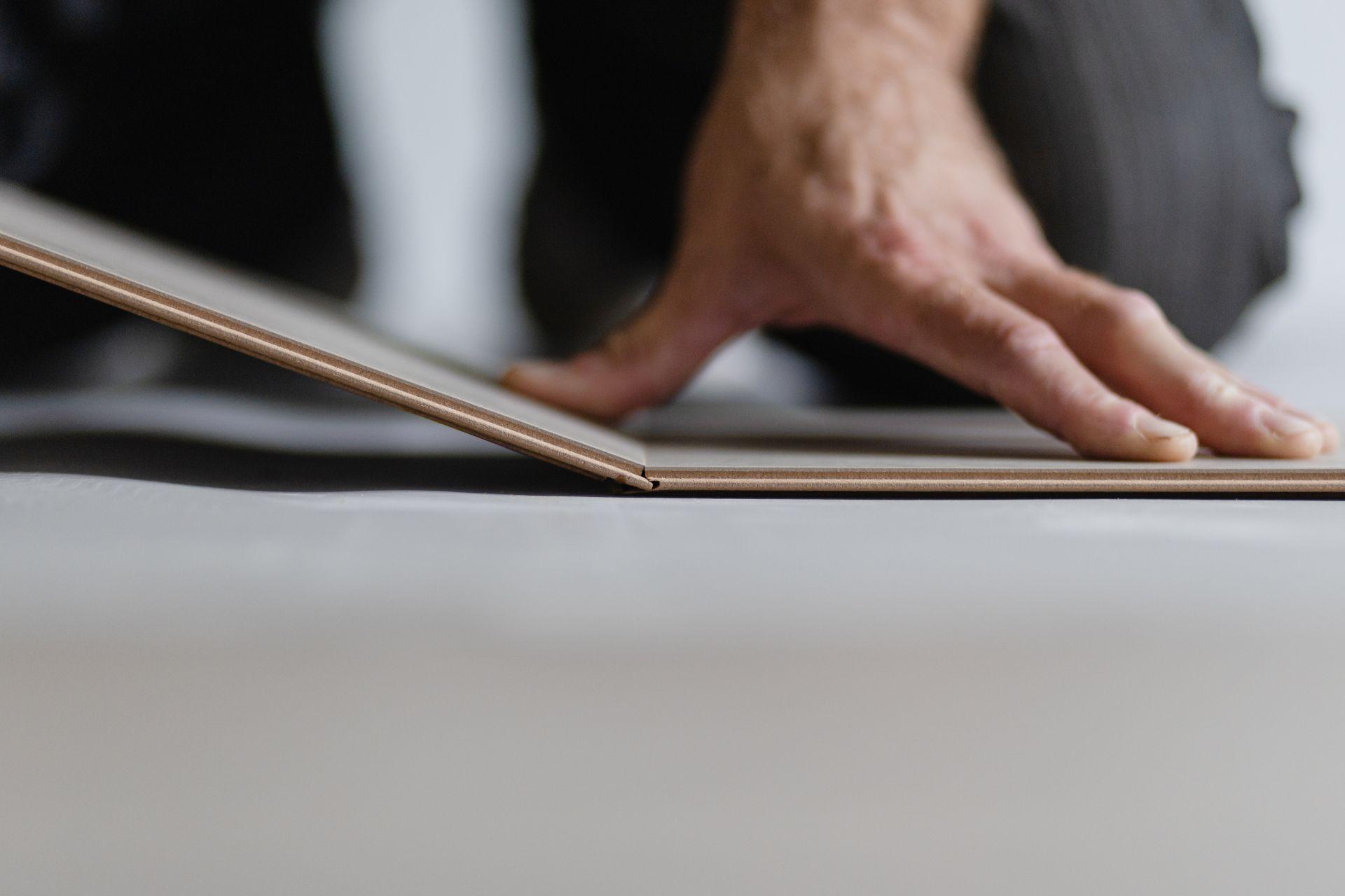 Nahaufnahme einer Hand bei der Verlegung einer Klickfliese auf ebenem Untergrund fuÌr schnelle und saubere Bodenmontage