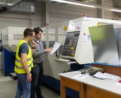 Mitarbeiter analysieren CNC-Maschine in Produktionshalle | Schweißrauchabsaugung