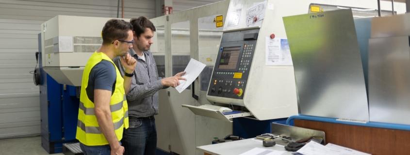 Mitarbeiter analysieren CNC-Maschine in Produktionshalle | Schweißrauchabsaugung